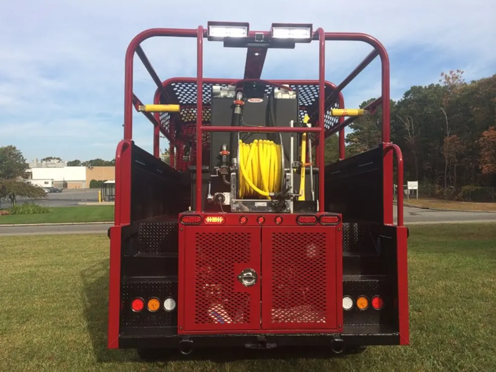 Exterior view of small fire truck showing cab, body compartments, and wheel/tire area.
