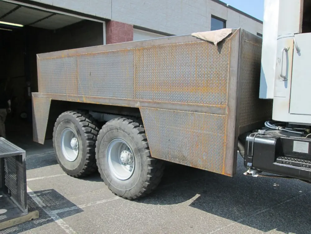 Exterior view of small fire truck showing cab, body compartments, and wheel/tire area.