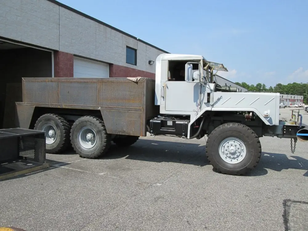 Exterior view of small fire truck showing cab, body compartments, and wheel/tire area.