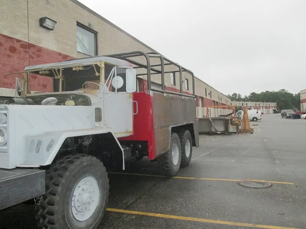 Exterior view of small fire truck showing cab, body compartments, and wheel/tire area.