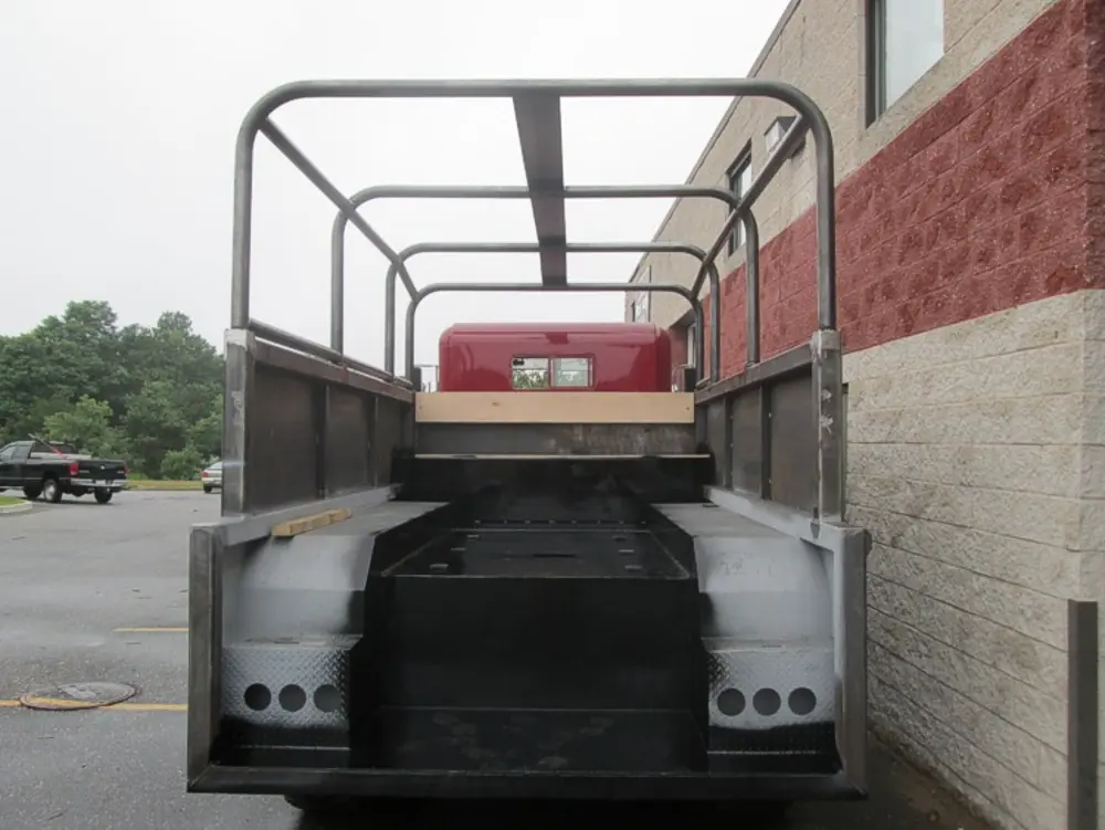 Exterior view of small fire truck showing cab, body compartments, and wheel/tire area.