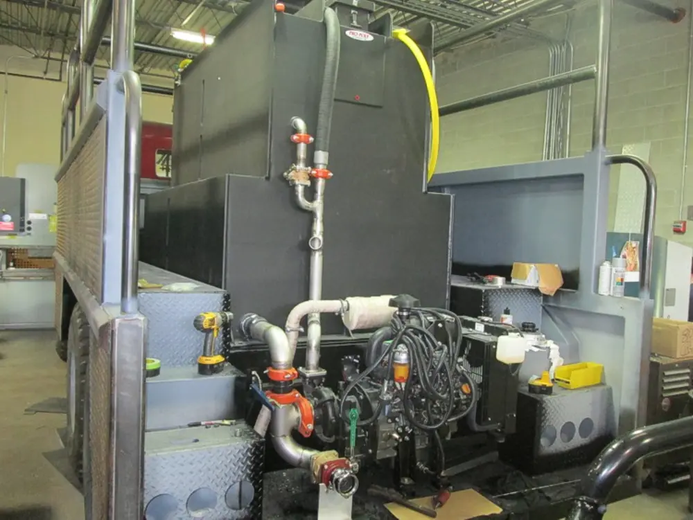 Exterior view of small fire truck showing cab, body compartments, and wheel/tire area.