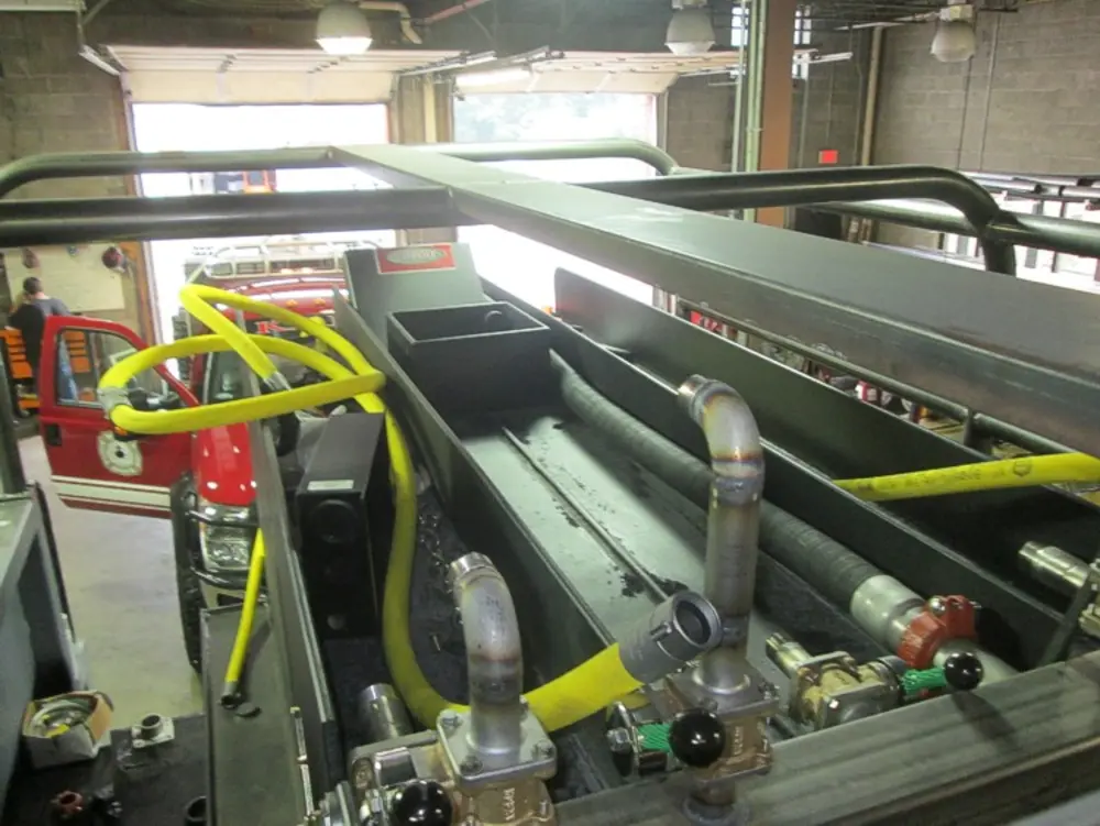 Exterior view of small fire truck showing cab, body compartments, and wheel/tire area.