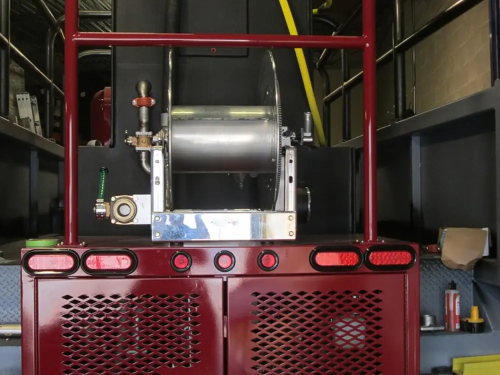 Exterior view of small fire truck showing cab, body compartments, and wheel/tire area.