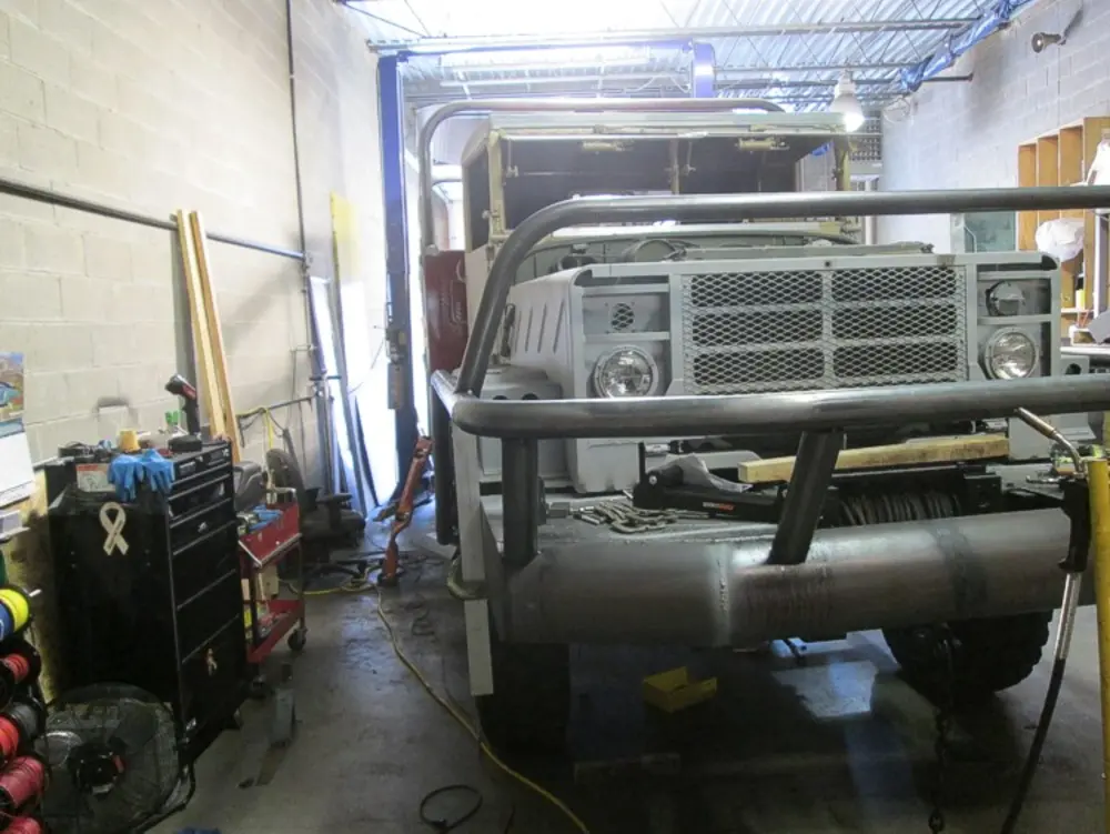 Exterior view of small fire truck showing cab, body compartments, and wheel/tire area.
