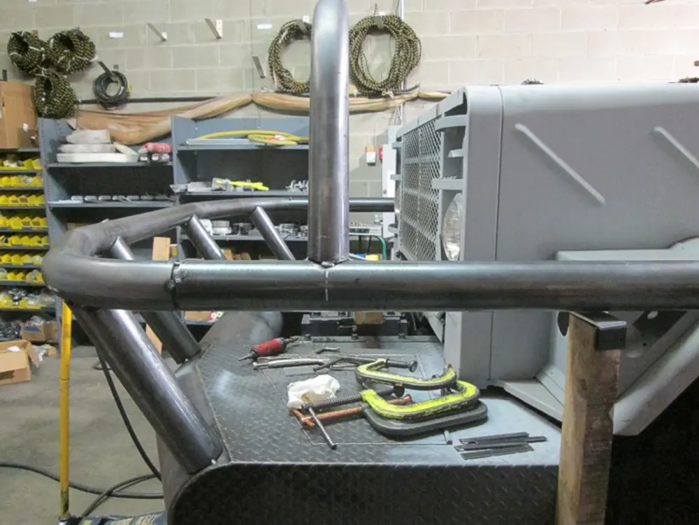 Exterior view of small fire truck showing cab, body compartments, and wheel/tire area.