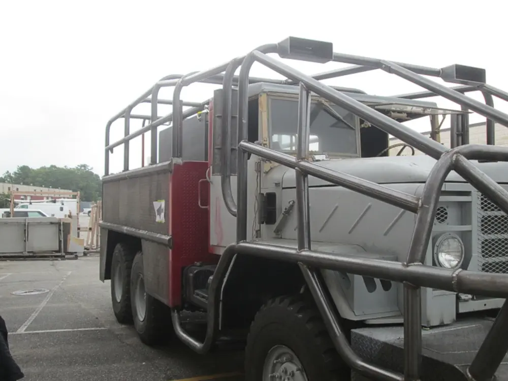 Exterior view of small fire truck showing cab, body compartments, and wheel/tire area.