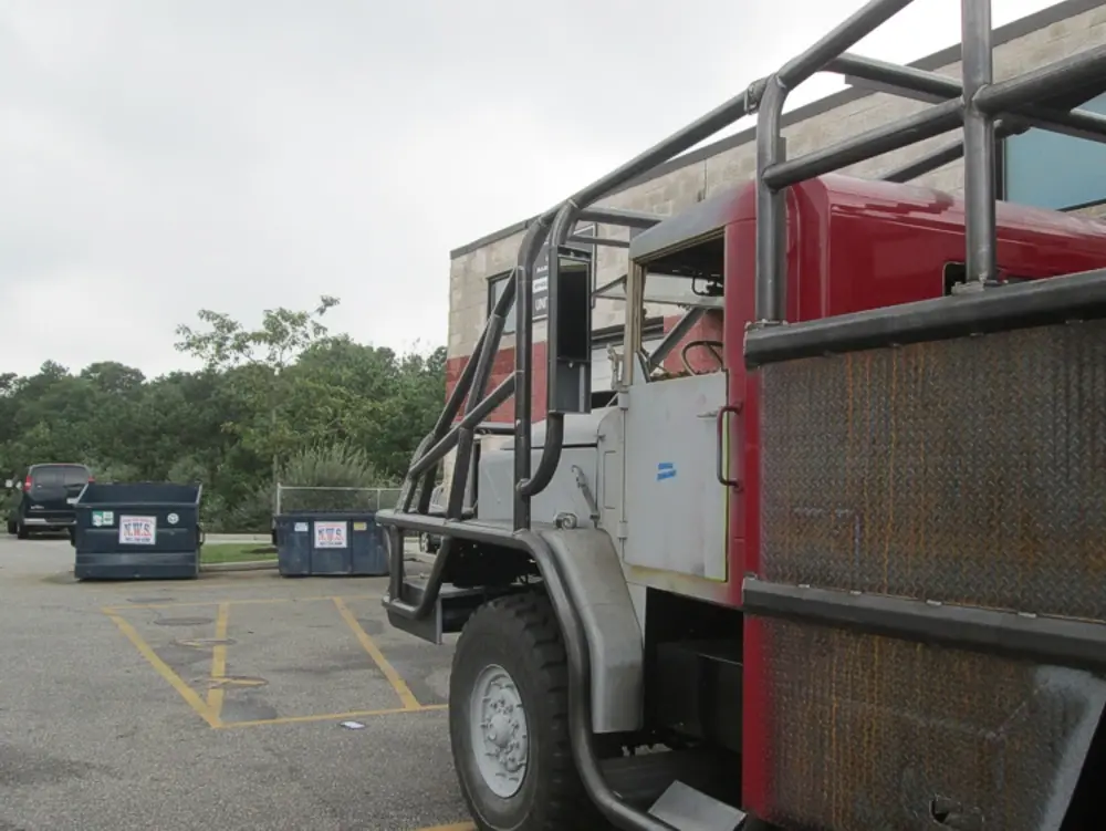 Exterior view of small fire truck showing cab, body compartments, and wheel/tire area.
