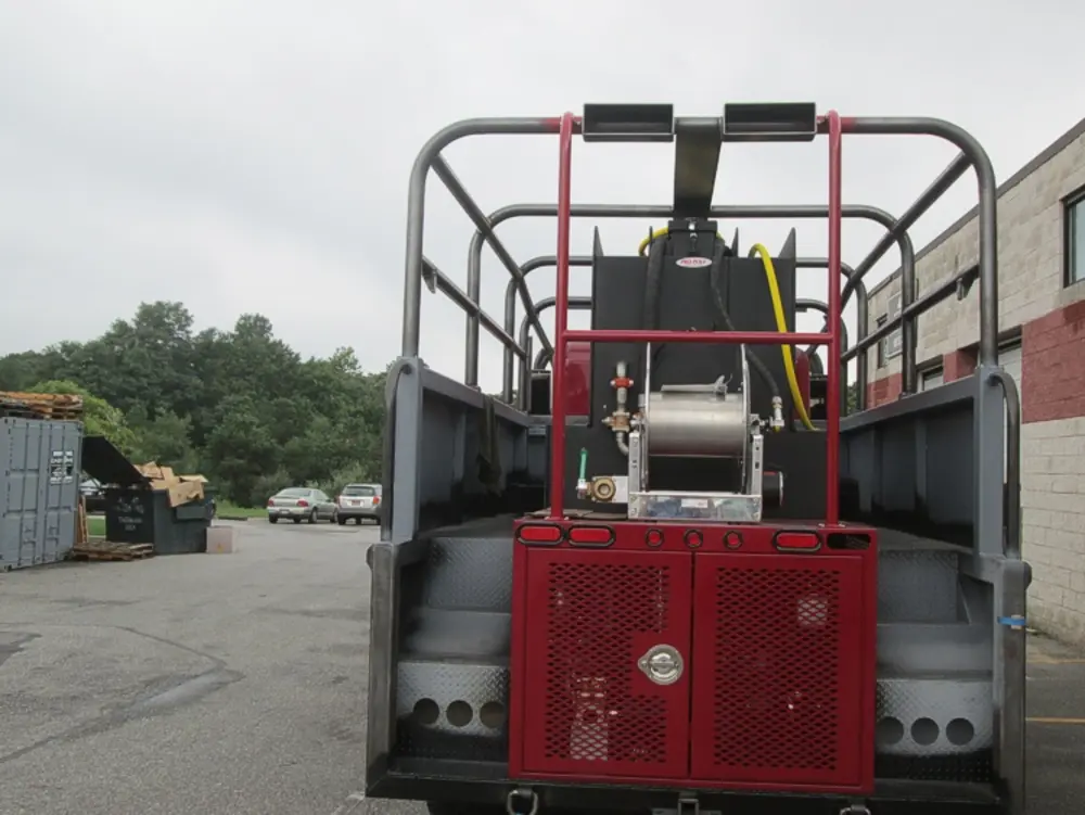 Exterior view of small fire truck showing cab, body compartments, and wheel/tire area.