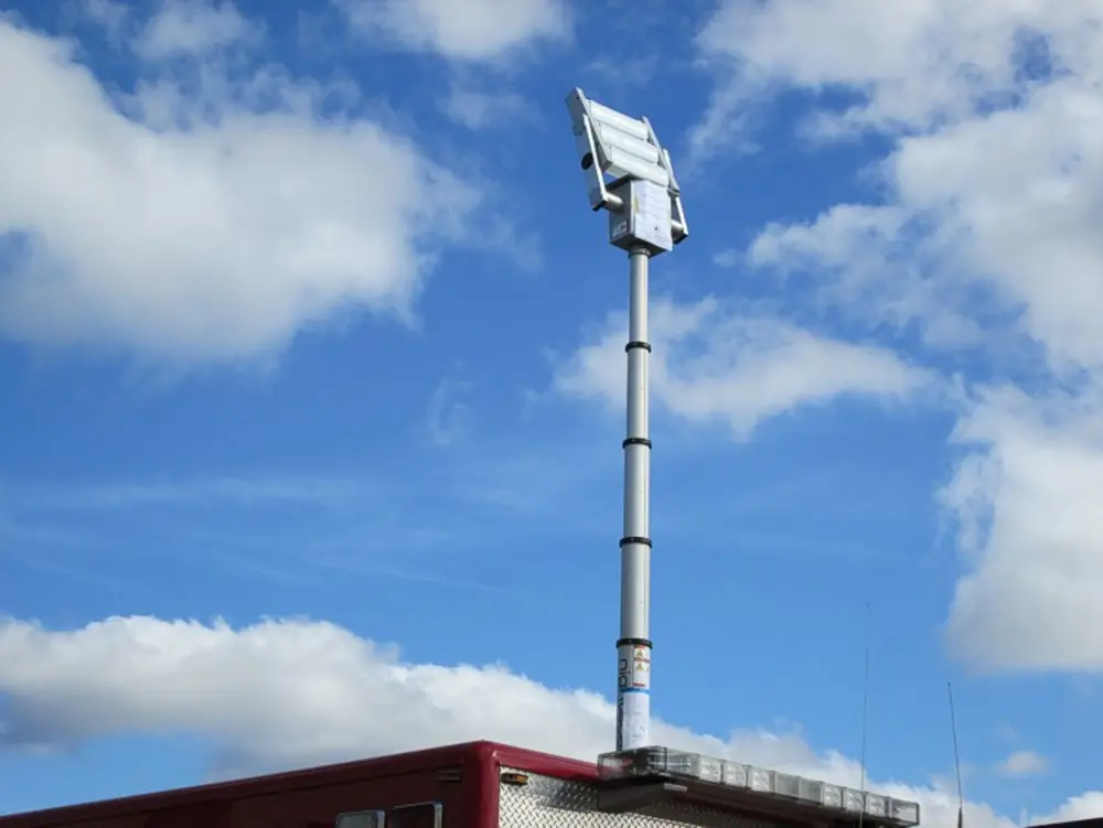 Exterior view of small fire truck showing cab, body compartments, and wheel/tire area.