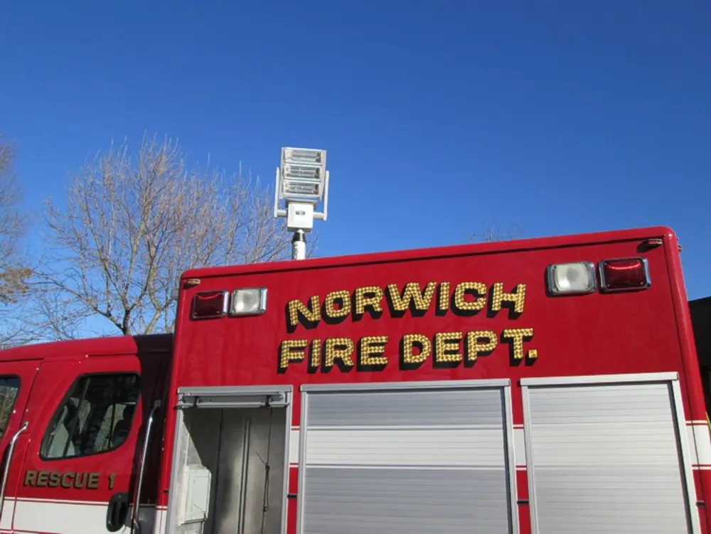 Exterior view of small fire truck showing cab, body compartments, and wheel/tire area.
