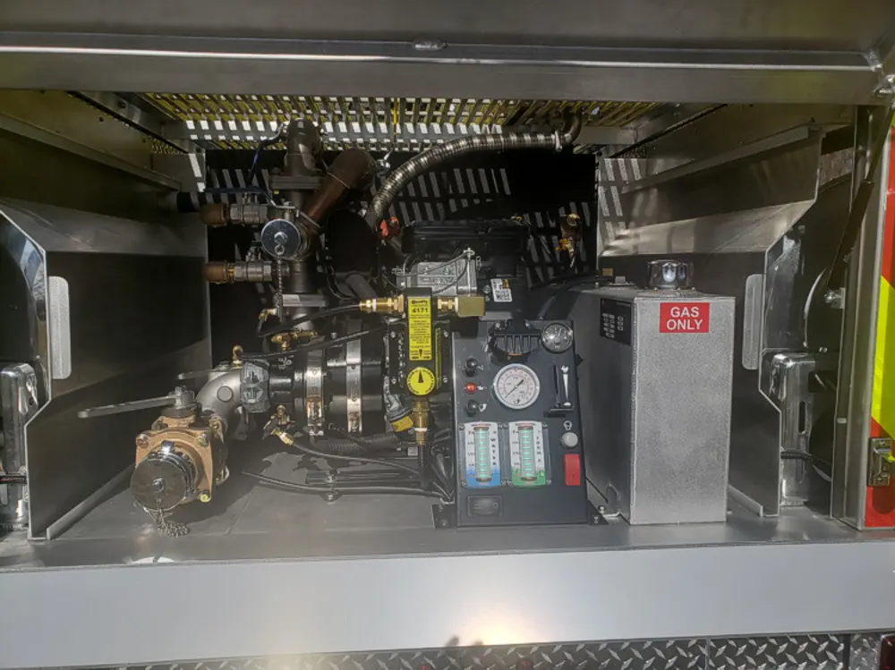 Exterior view of small fire truck showing cab, body compartments, and wheel/tire area.