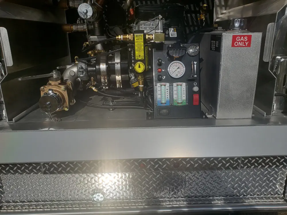 Exterior view of small fire truck showing cab, body compartments, and wheel/tire area.