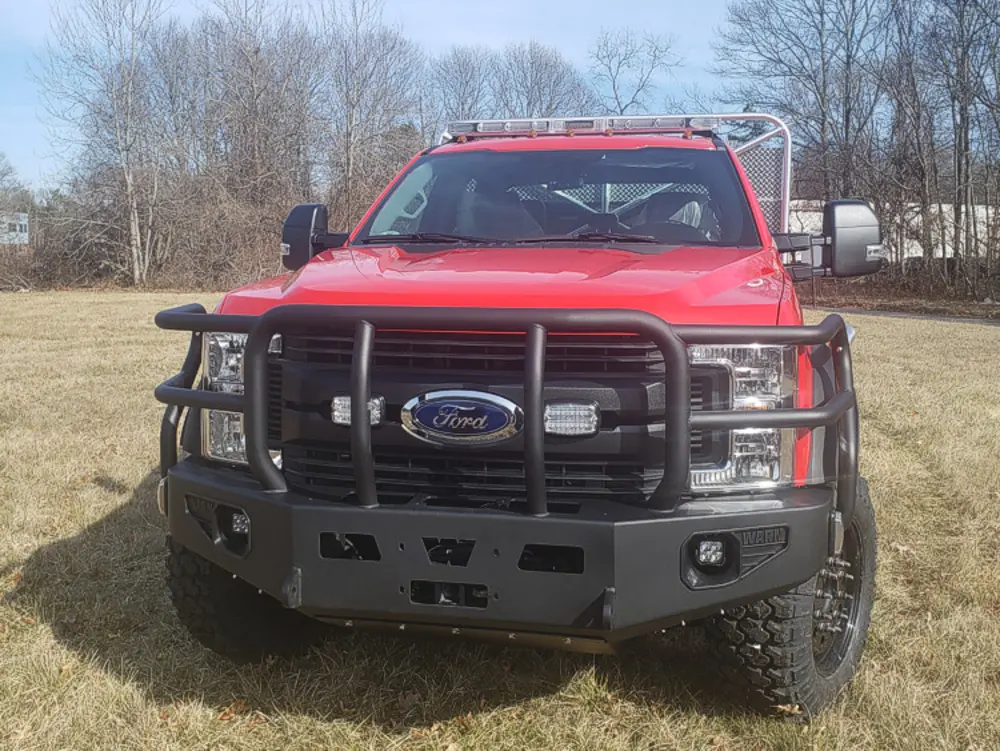 Exterior view of small fire truck showing cab, body compartments, and wheel/tire area.