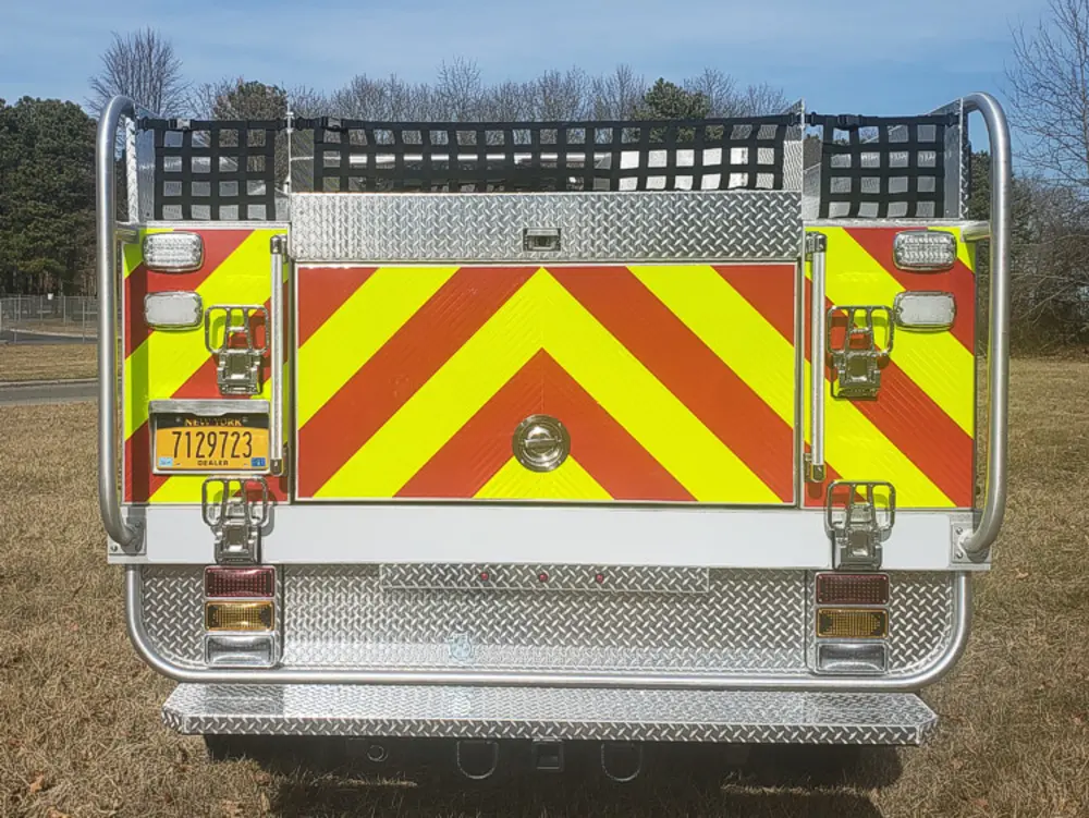 Exterior view of small fire truck showing cab, body compartments, and wheel/tire area.