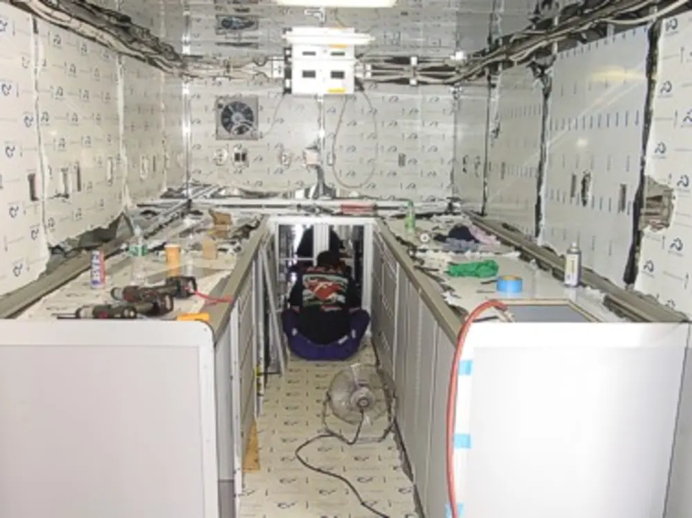 Exterior view of small fire truck showing cab, body compartments, and wheel/tire area.