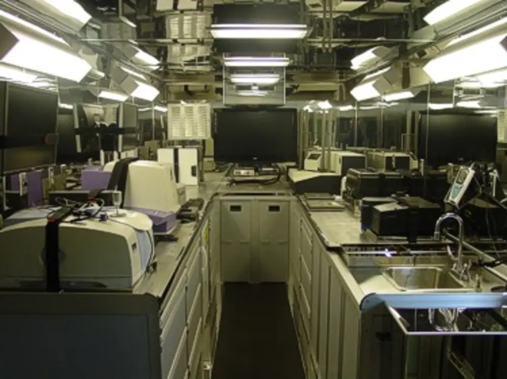 Exterior view of small fire truck showing cab, body compartments, and wheel/tire area.