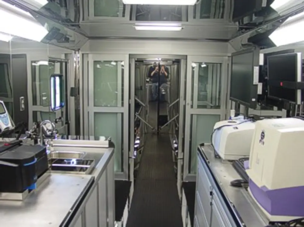 Exterior view of small fire truck showing cab, body compartments, and wheel/tire area.