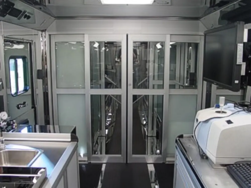 Exterior view of small fire truck showing cab, body compartments, and wheel/tire area.