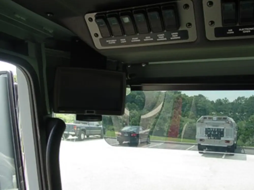 Exterior view of small fire truck showing cab, body compartments, and wheel/tire area.