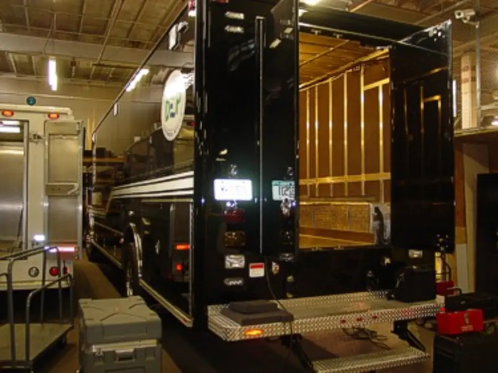 Exterior view of small fire truck showing cab, body compartments, and wheel/tire area.