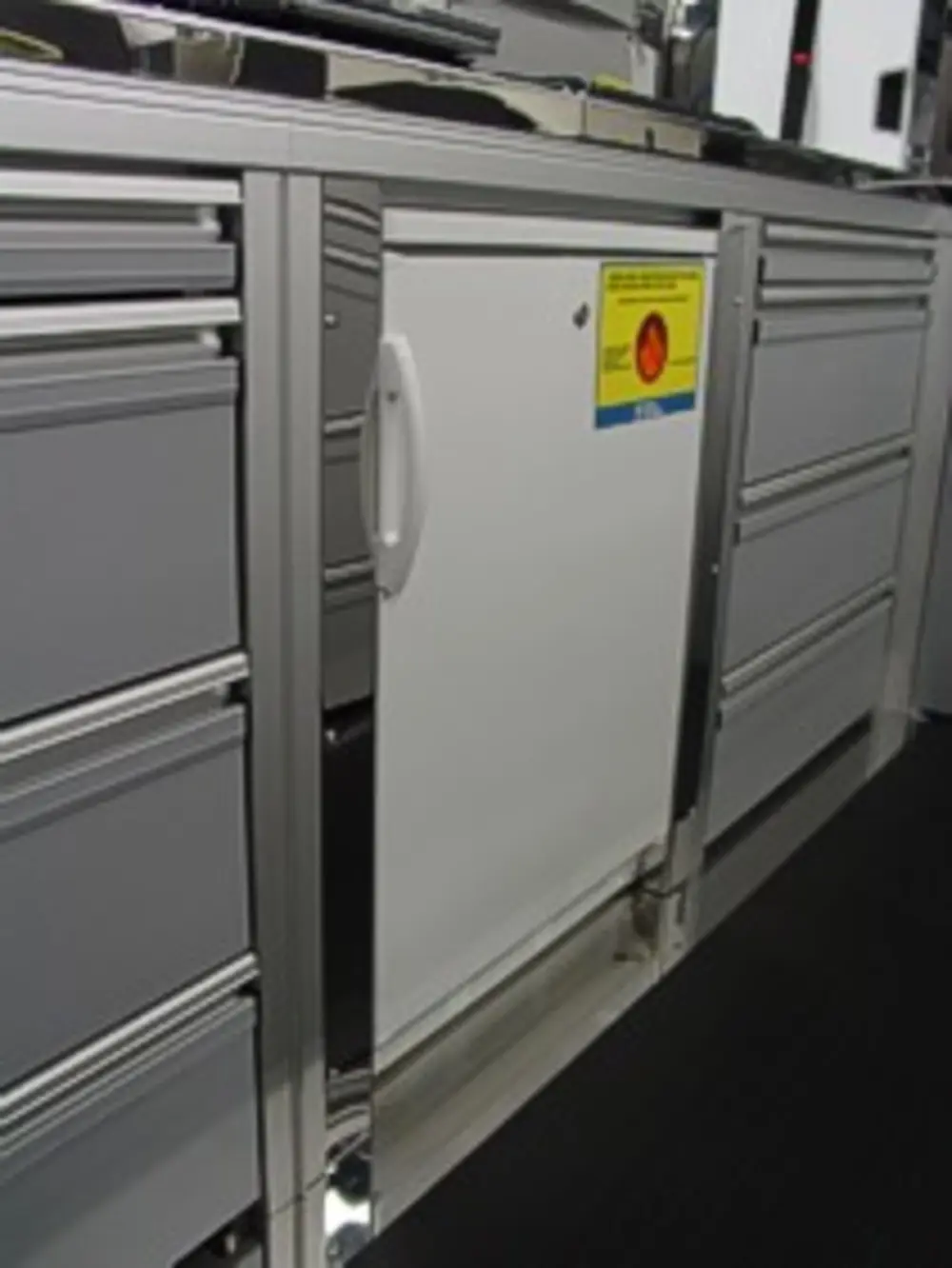 Exterior view of small fire truck showing cab, body compartments, and wheel/tire area.