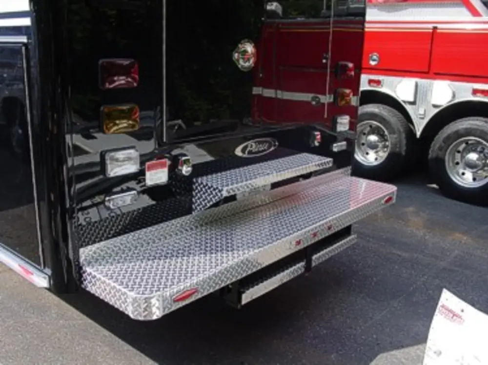 Exterior view of small fire truck showing cab, body compartments, and wheel/tire area.