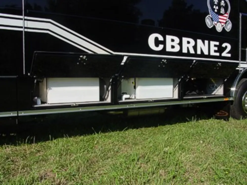Exterior view of small fire truck showing cab, body compartments, and wheel/tire area.