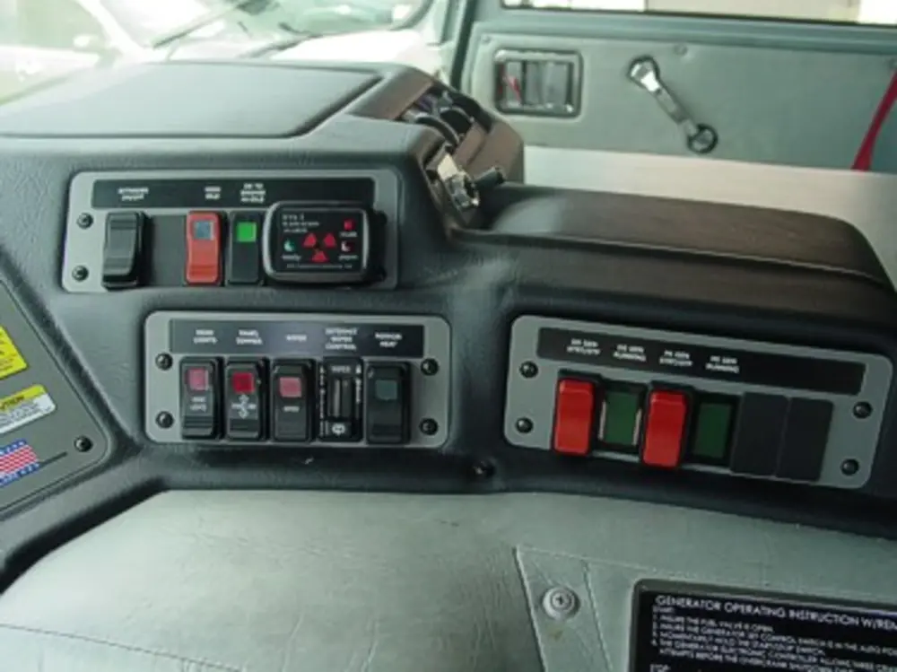 Exterior view of small fire truck showing cab, body compartments, and wheel/tire area.