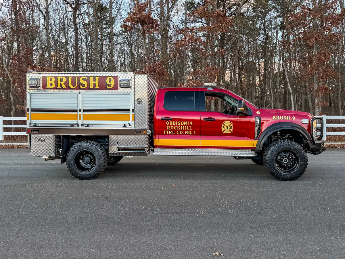 Driver-side profile of brush truck parked on road.