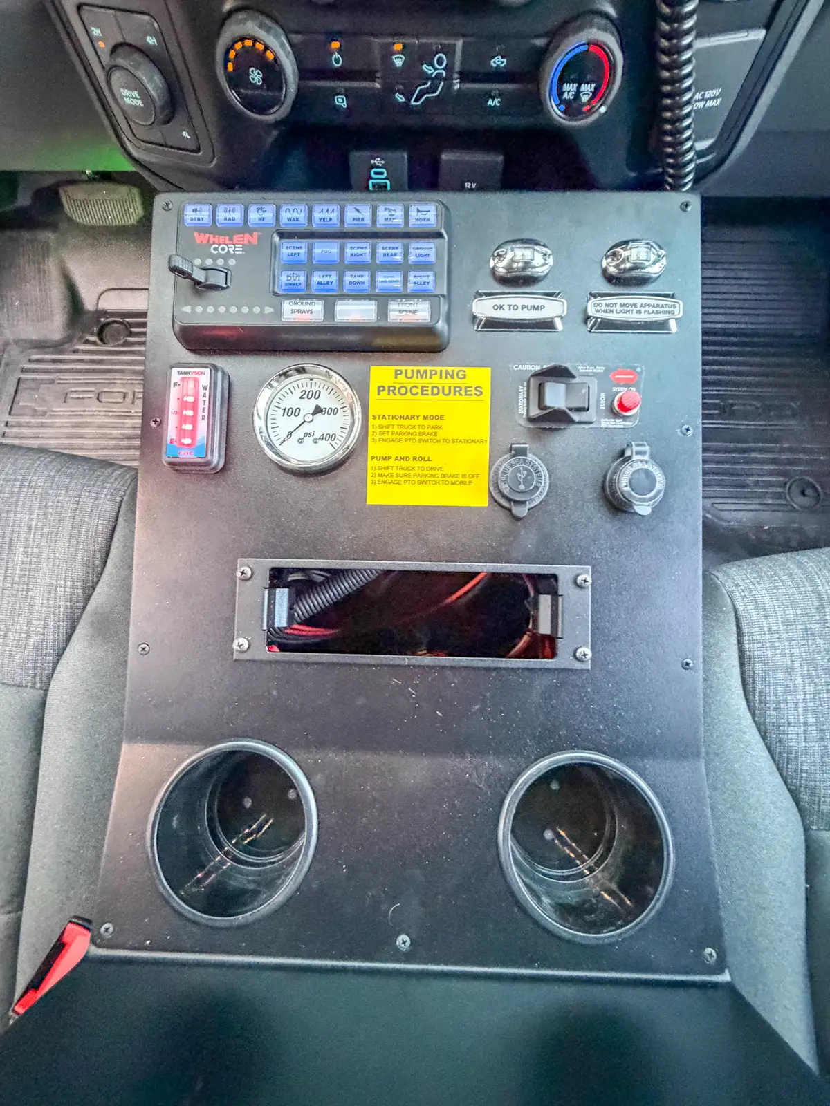 Console control surface with switches, labels, and cupholders.