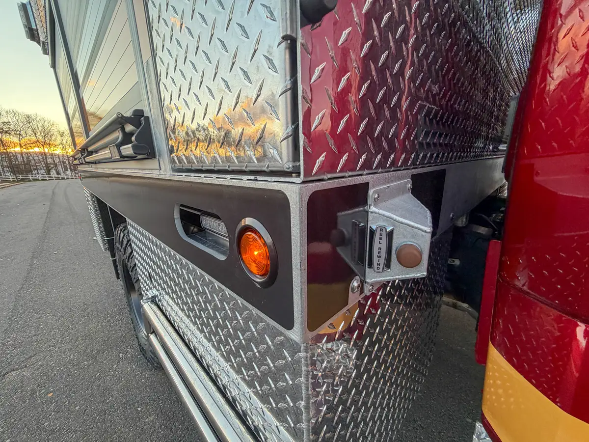 Rear side corner close-up with marker light and outlet fitting.