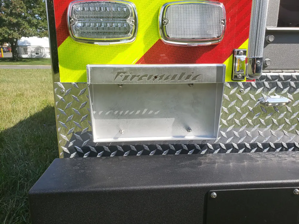 Exterior view of small fire truck showing cab, body compartments, and wheel/tire area.
