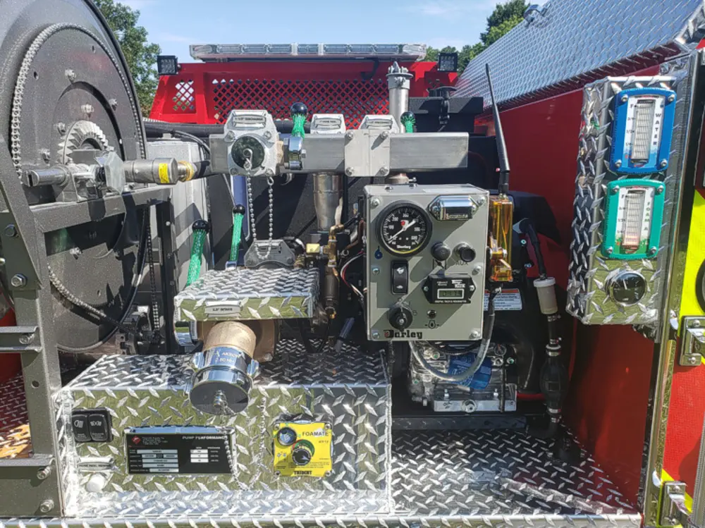 Exterior view of small fire truck showing cab, body compartments, and wheel/tire area.
