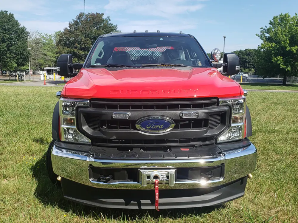Exterior view of small fire truck showing cab, body compartments, and wheel/tire area.