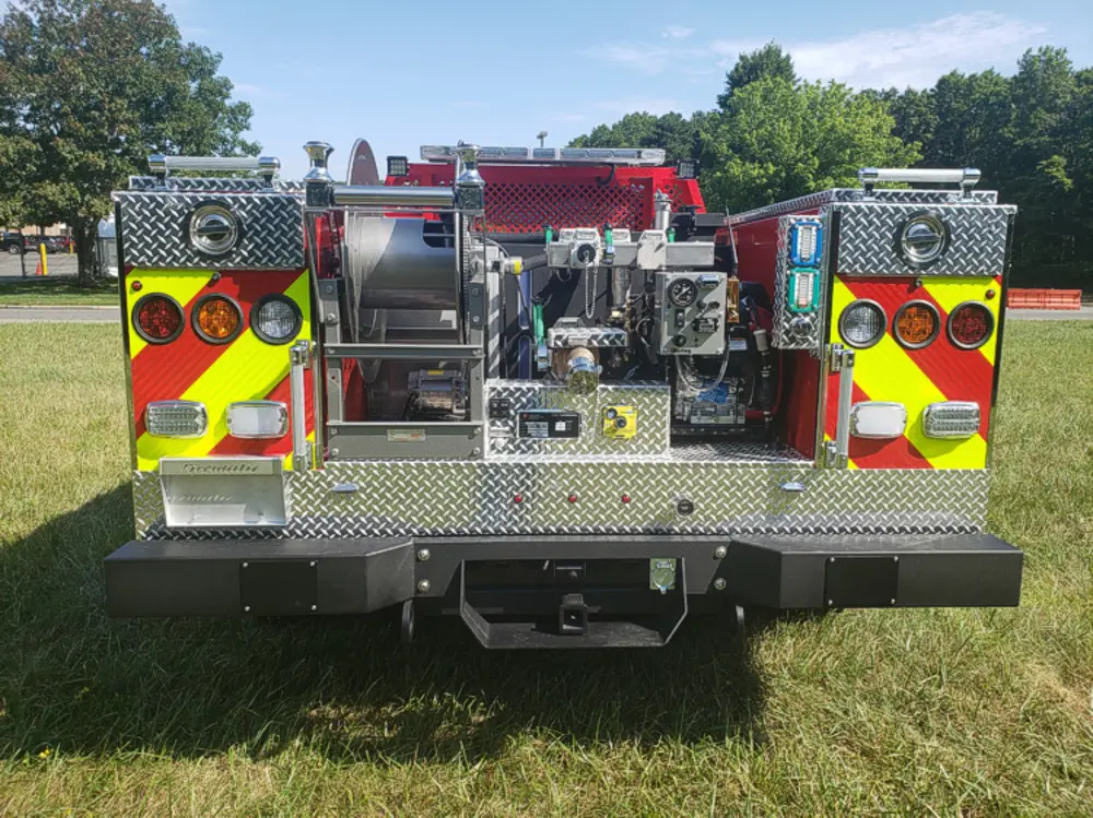 Exterior view of small fire truck showing cab, body compartments, and wheel/tire area.
