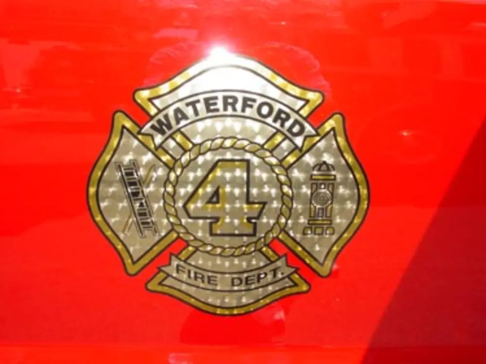 Exterior view of small fire truck showing cab, body compartments, and wheel/tire area.