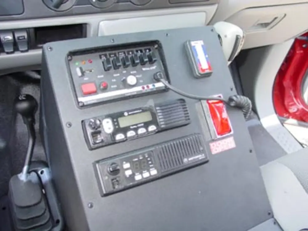 Exterior view of small fire truck showing cab, body compartments, and wheel/tire area.