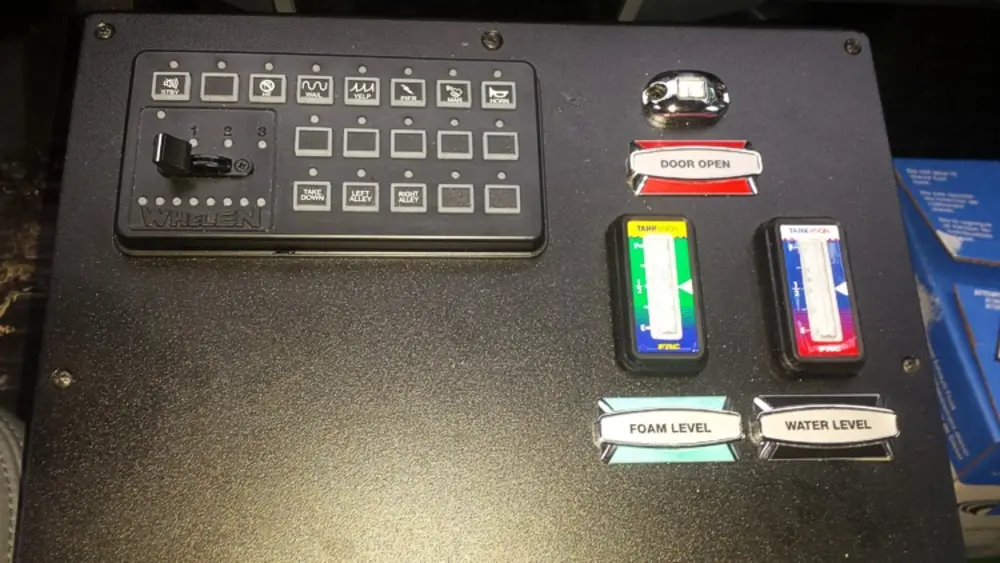 Exterior view of small fire truck showing cab, body compartments, and wheel/tire area.