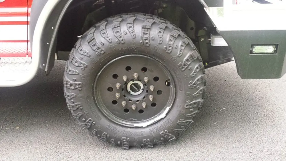 Exterior view of small fire truck showing cab, body compartments, and wheel/tire area.