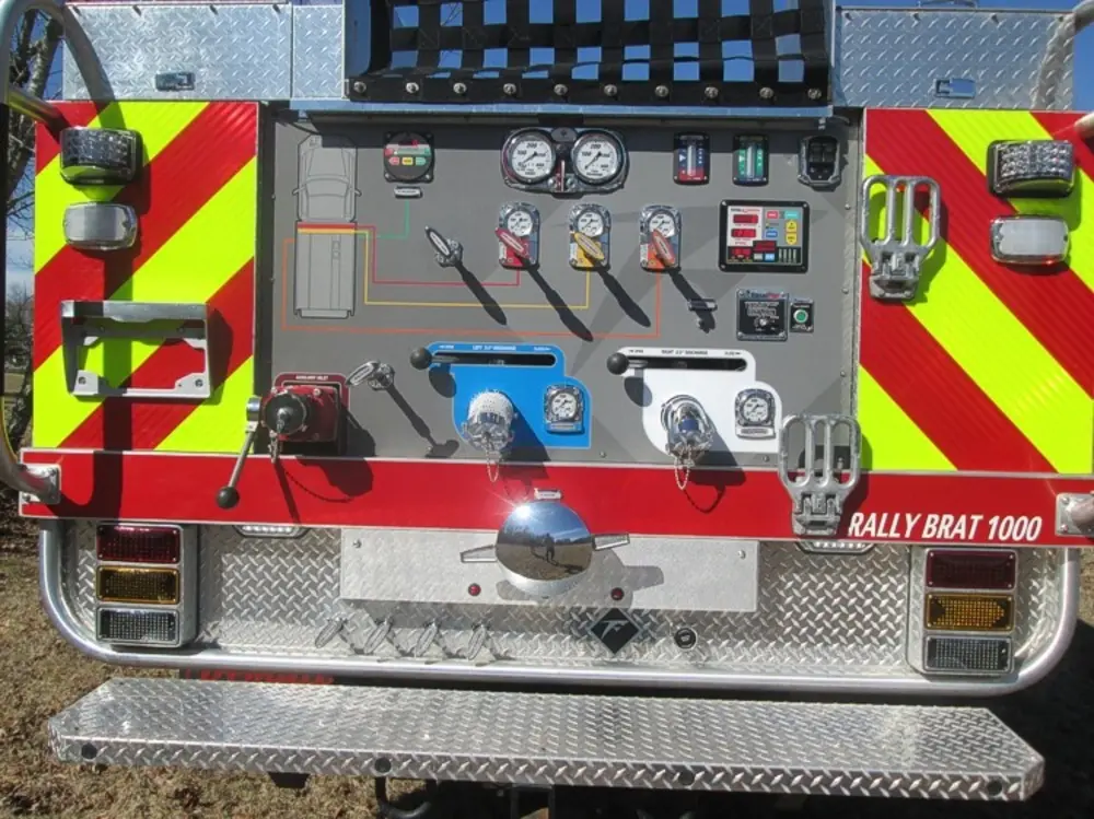 Exterior view of small fire truck showing cab, body compartments, and wheel/tire area.