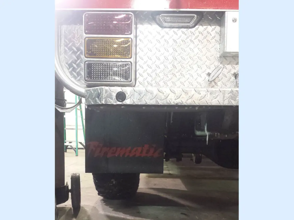 Exterior view of small fire truck showing cab, body compartments, and wheel/tire area.