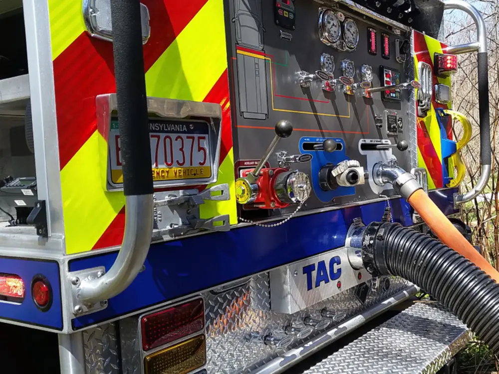 Exterior view of small fire truck showing cab, body compartments, and wheel/tire area.