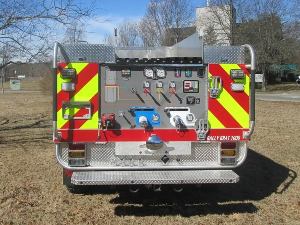 Exterior view of small fire truck showing cab, body compartments, and wheel/tire area.