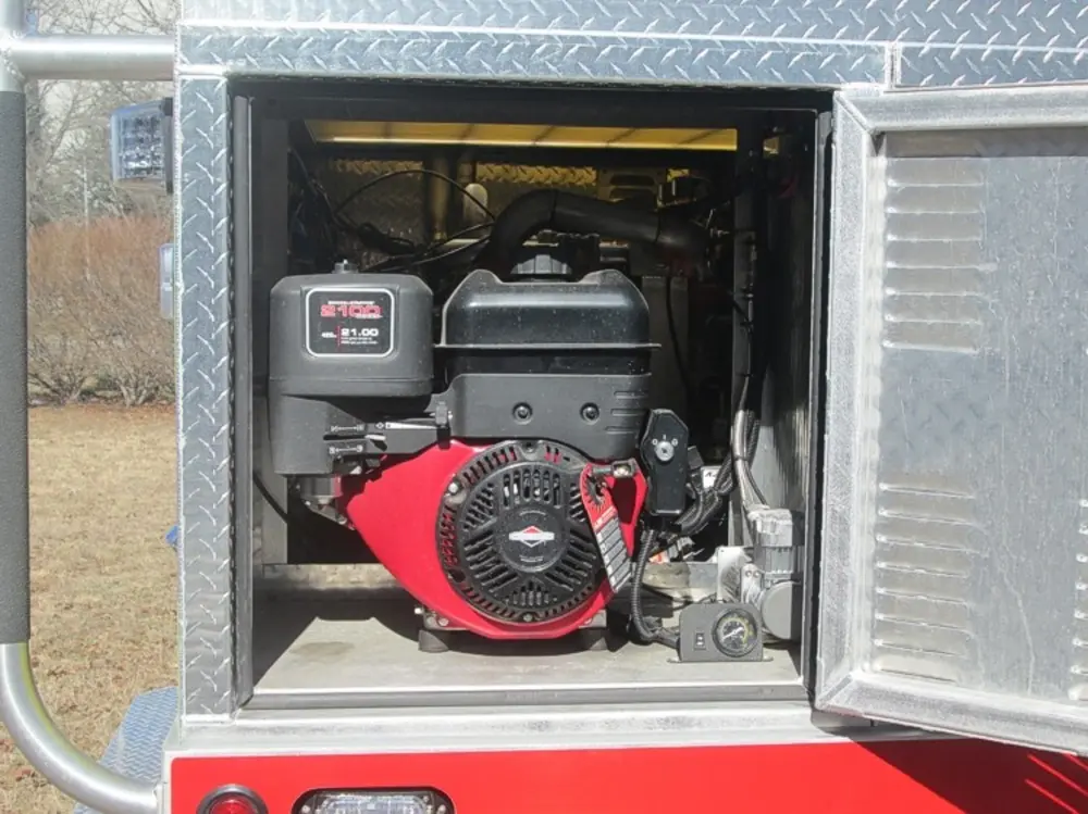 Exterior view of small fire truck showing cab, body compartments, and wheel/tire area.