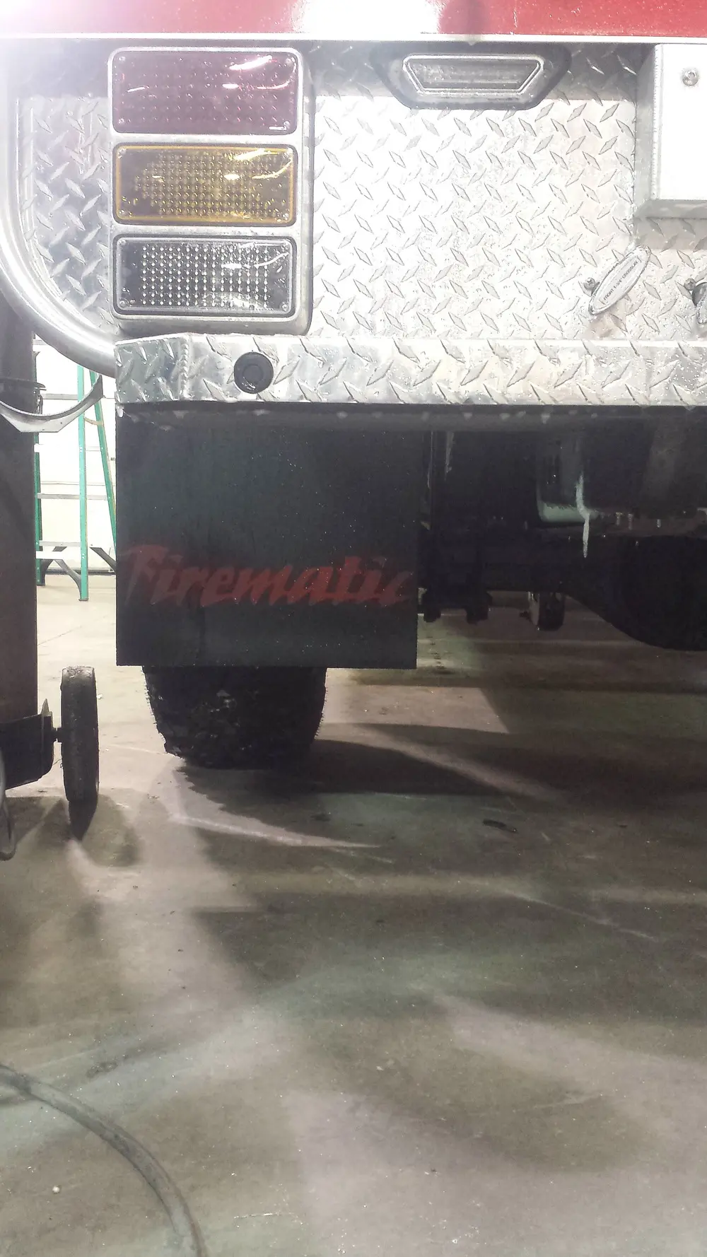 Exterior view of small fire truck showing cab, body compartments, and wheel/tire area.