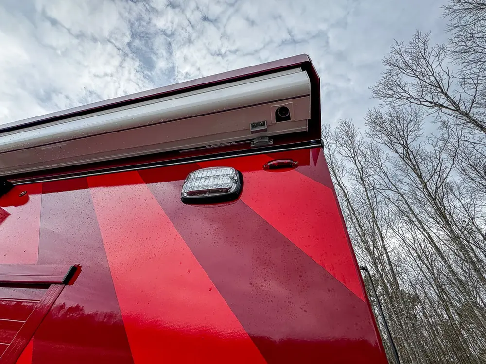 Exterior view of small fire truck showing cab, body compartments, and wheel/tire area.