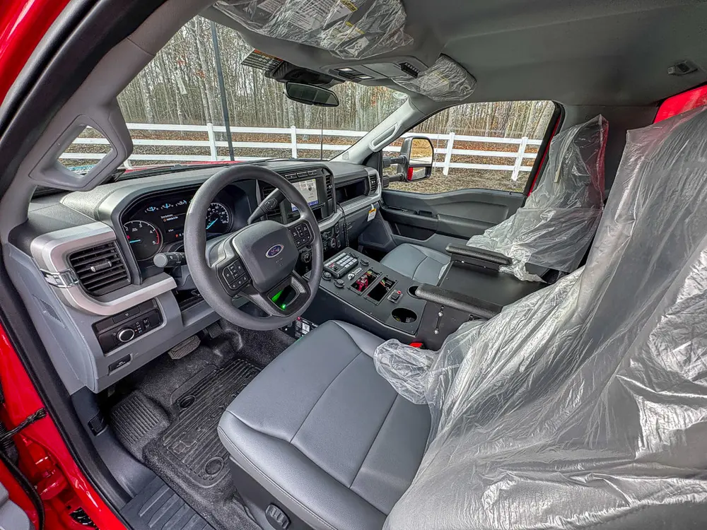 Exterior view of small fire truck showing cab, body compartments, and wheel/tire area.