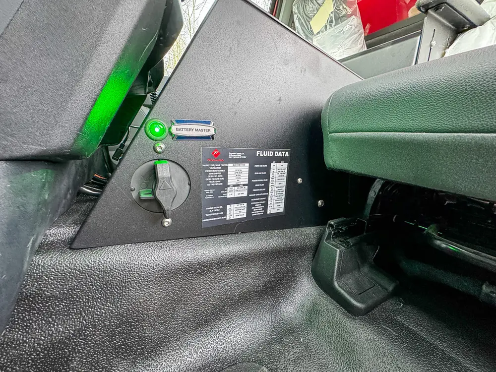 Exterior view of small fire truck showing cab, body compartments, and wheel/tire area.