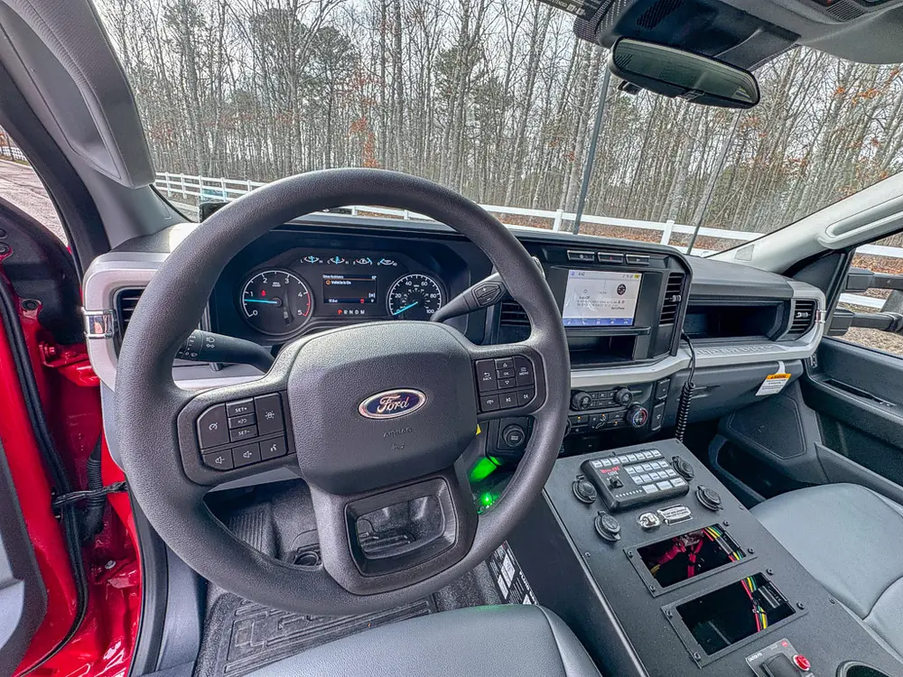 Exterior view of small fire truck showing cab, body compartments, and wheel/tire area.